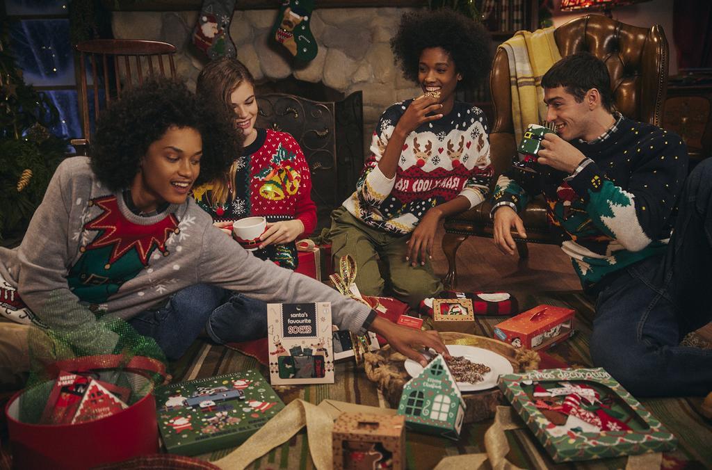 Cuatro jovenes de la serie The Cosby Show sentados en una mesa llevando el ugly sweater